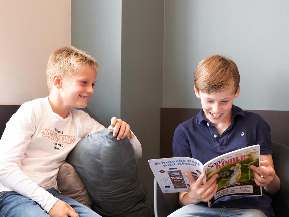 Zwei Jungs schauen sich gerade im Wartezimmer eine Zeitschrift an.